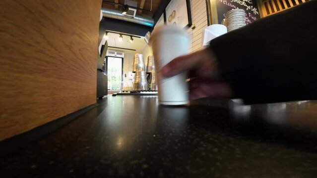 Low-angle shot inside a cafe with a person reaching for a takeaway cup at Starbucks.