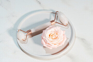 Rose quartz face roller on marble background, top view. mockup with facial massage tool. Skin care, body treatment and spa concept