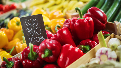 100% Bio Sign on a Food Stall with Fresh Red and Yellow Organic Sweet Bell Peppers from a Local...