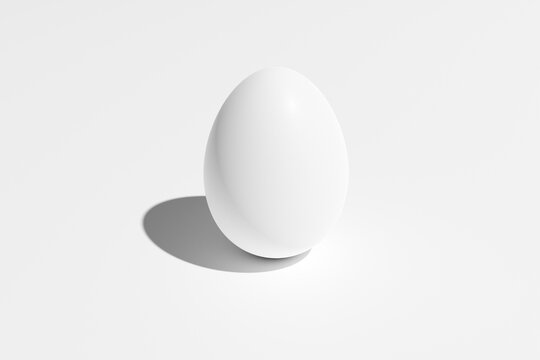 A white chicken egg stands vertically on a white background.