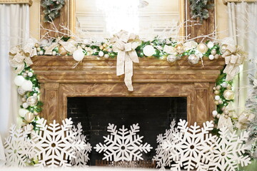Festive arrangement of snowflakes and various Christmas ornaments adorning a cozy fireplace