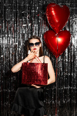 Young fashion Girl in dress with Valentine Heart shaped balloon and gift on party background. Love. Valentines Day gift.
