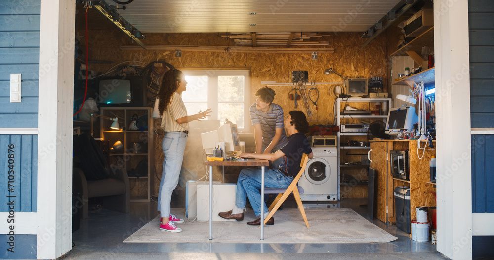Fototapete diverse team of three young tech startup company founders working in retro garage, using old desktop
