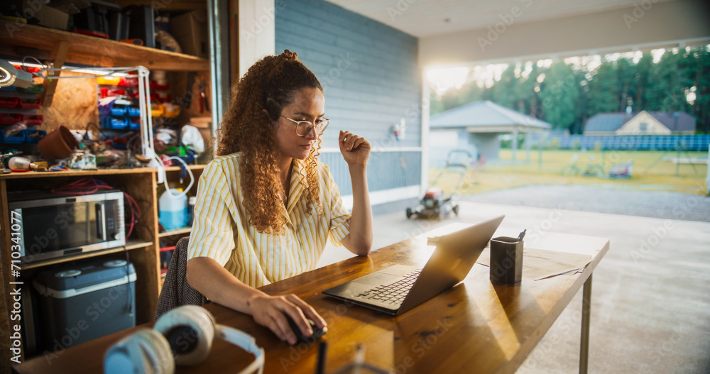 Aufkleber Young Hispanic Female Software Engineer Programming On Laptop Computer In Opened Garage. Woman Running A Startup With Innovative SaaS Solution For Businesses. Developer Writing Code, Optimizing System