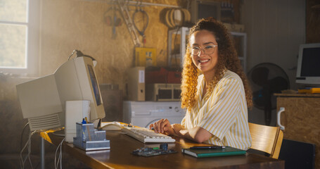 Hispanic Female Software Engineer Programming On Old Desktop Computer In Retro Garage, Looking At...