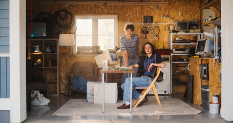 Two Caucasian Male Tech Startup Founders Using Old Desktop Computer In Retro Garage, Looking At...