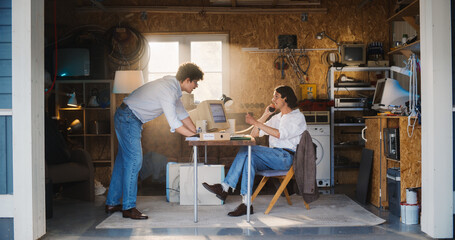Two Caucasian Male Stock Brokers Working In Retro Garage, Using Old Desktop Computer With Candlestick Chart And Landline Phone To Pitch A Public Company To Investor. Partners Trading On Stock Exchange