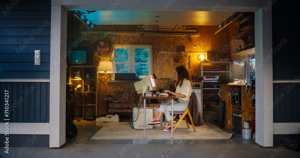 Poster Hispanic Female Software Developer Programming On Old Desktop Computer In Retro Garage In the Evening. Woman Working On Innovative Online Service Startup Company In Nineties. Nostalgia Concept.