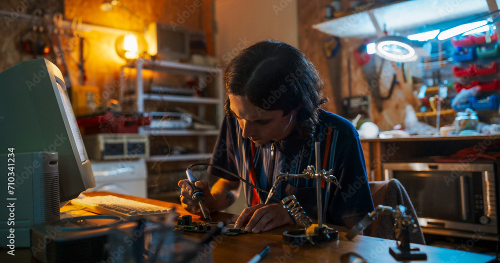 Poster portrait of caucasian male engineer using soldering iron on circuit board in front of old desktop co