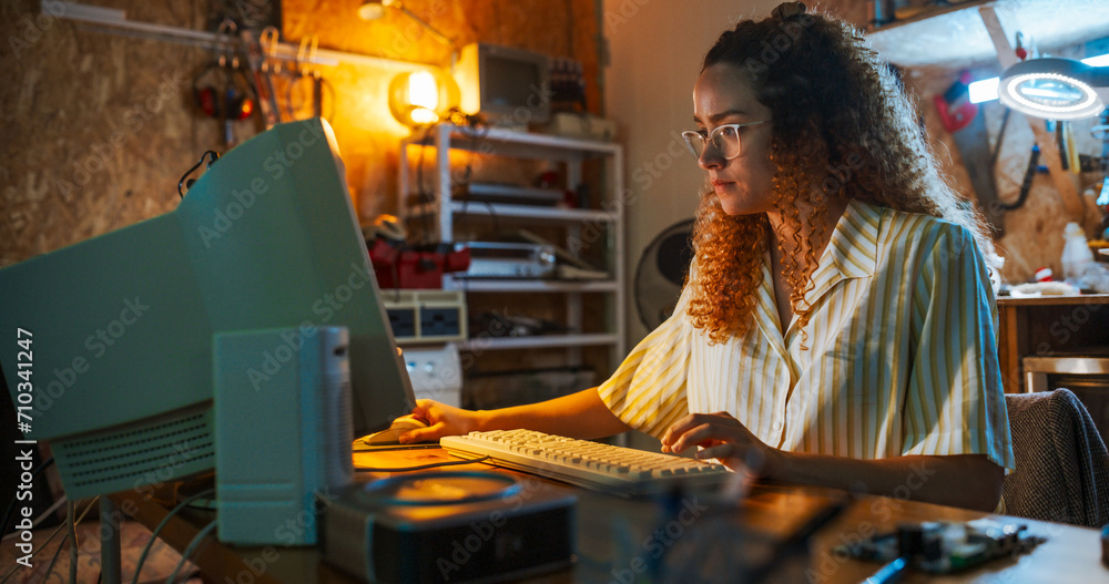 Leinwandbilder Hispanic Female Engineer Using Old Desktop Computer In Nineties Retro Garage In The Evening. Intelligent Woman Programming, Working On Innovative Portable Device, Starting Tech Startup Company.
