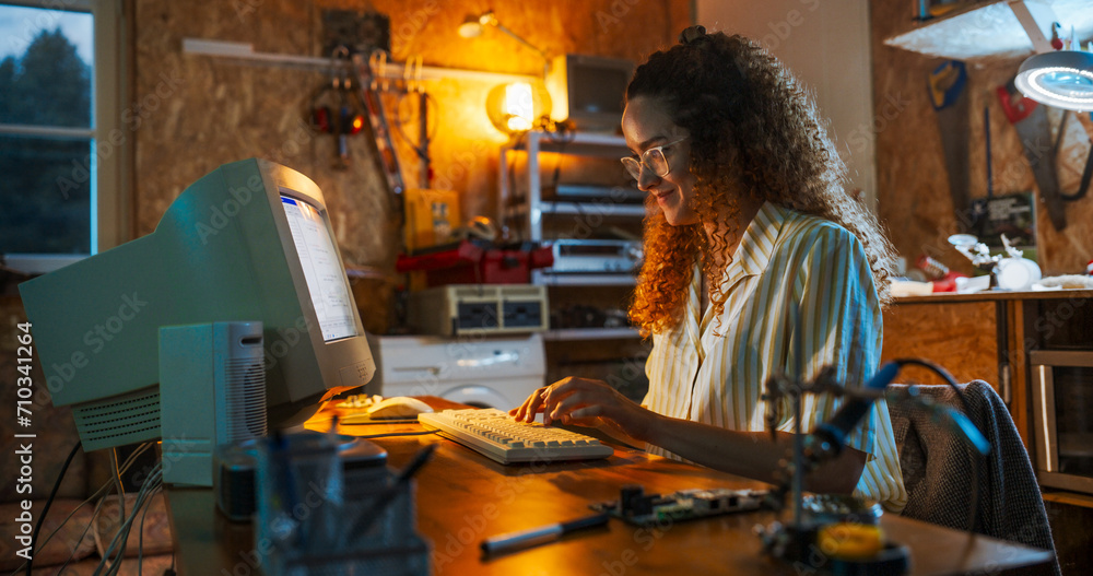 Poster hispanic female engineer using old desktop computer in nineties retro garage in the evening. intelli
