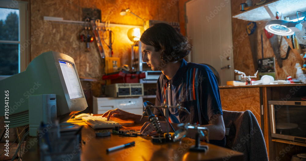 Poster Portrait Of Caucasian Male Software Engineer Programming on Old Desktop Computer In Retro Garage In The Evening. Man Starting Tech Startup Company In Nineties. Coding Innovative Online Service At Home