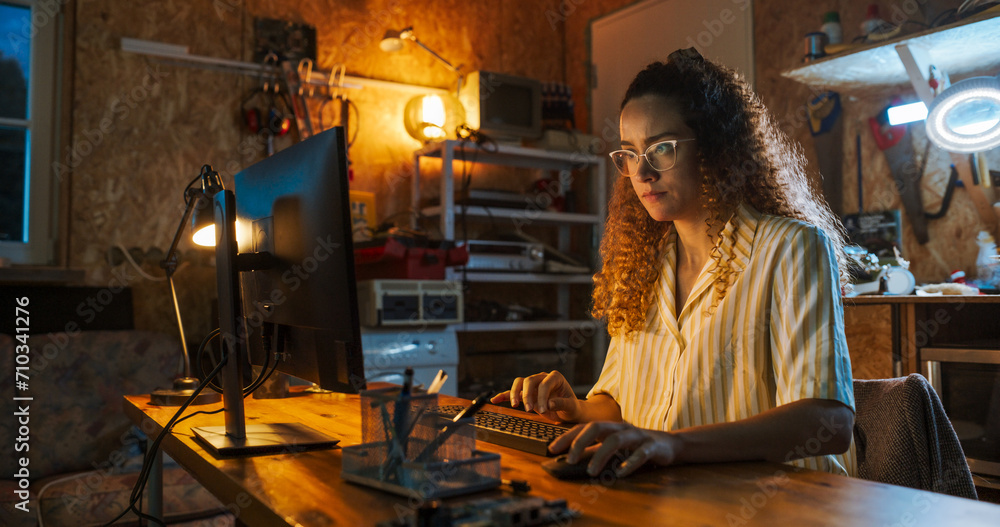 Aufkleber Hispanic Female Software Engineer Programming on Desktop Computer In Retro Garage Late At Night. Ambitious Woman Starting Technological Startup Company. Coding Innovative Online Service At Home.