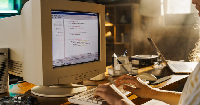 Side View Of Hispanic Female Engineering Student Writing Academic Thesis On Old Desktop Computer In Retro Garage. Future Engineer Focused On Innovative Project For University Of Technology In Nineties - Powered by Adobe