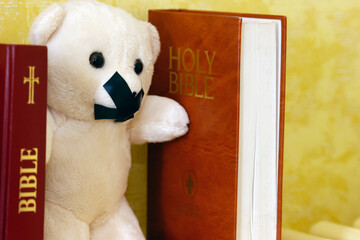 Bibles and teddy bear with tape on his mouth. Symbol of silence on child abuse and victim in...