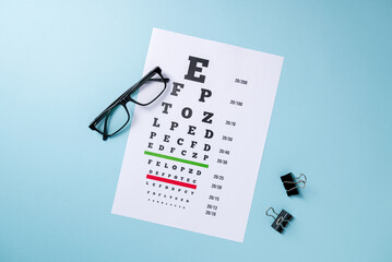 Eye test chart and glasses on blue background