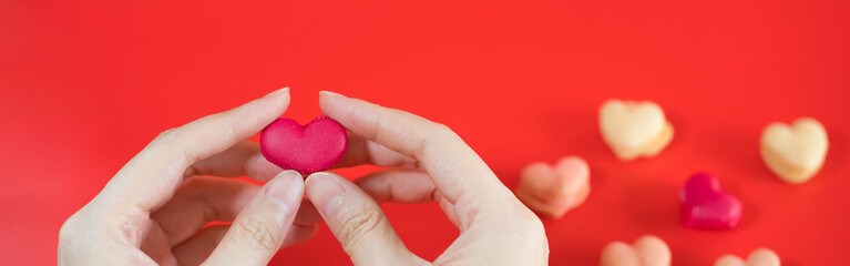 flat lay heart shape of macarons on hand with red background