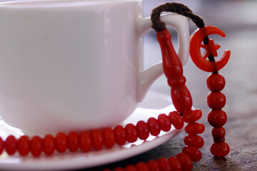 Red tasbih ( muslim prayer beads ) with star and crescent  on a cup of coffee. .