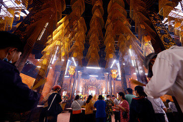 Fototapeta na wymiar Canton Assembly Hall of Can Tho. Buddhist believers praying with incense sticks. Can Tho. Vietnam.