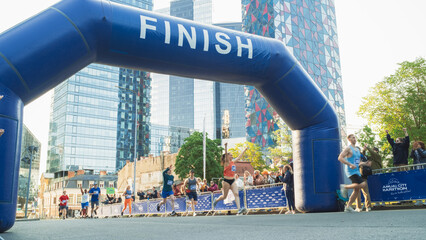 Wide Shot of a Diverse Group of Runners Participating in a City Marathon: Participants Arriving at the Finish Line, Celebrating With the Cheers of their Friends and Family in the Audience - Powered by Adobe