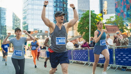 Portrait of Smiling Middle Aged Man Running in a City Marathon, Waving at the Supportive Audience. Friendly Happy Male Runner Celebrating Crossing the Finish Line in a Race - obrazy, fototapety, plakaty
