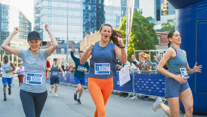 Women Supporting Women: Portrait of Happy Female Runners Participating in a Marathon. Group of Friends Celebrating Together and Congratulating Each Other on Crossing the Finish Line - obrazy, fototapety, plakaty