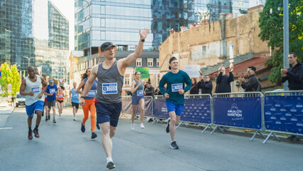 Portrait of Smiling Middle Aged Man Running in a City Marathon, Waving at the Supportive Audience. Friendly Happy Male Runner Celebrating Crossing the Finish Line in a Race