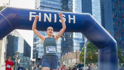 Portrait of a Happy Female City Marathon Runner Crossing the Finish Line and Celebrating her...
