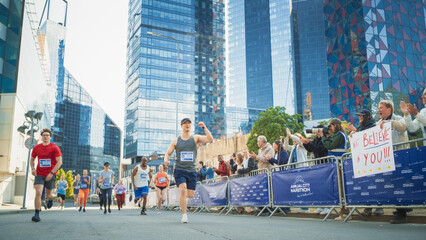 Portrait of Smiling Middle Aged Man Running in a City Marathon, Waving at the Supportive Audience. Friendly Happy Male Runner Celebrating Crossing the Finish Line in a Race