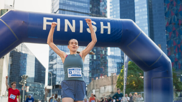 Portrait of a Happy Female City Marathon Runner Crossing the Finish Line and Celebrating her Victory. Female Race Winner Achieving her Goal and Enjoys her Accomplishement  