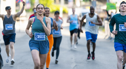 Diverse Group of People Running a Marathon in a City During the Day. Active and Fit Smiling Female...