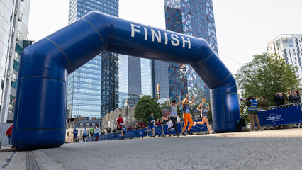 Smiling Group of People Participating in a City Marathon. Wide Shot of Diverse Race Runners Reaching the Finish Line, Celebrating Their Victory and Achieving their Goal