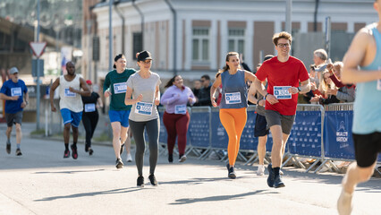 Smiling Group of People Participating in a City Marathon. Diverse Race Runners Reaching the Finish...