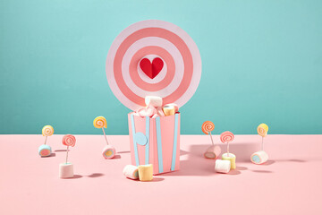 Lovely and girly style with a composition of pink and blue paper bucket, a bullseye with red heart and many marshmallows decorated. Hearts symbol of love, romantic holiday concept - obrazy, fototapety, plakaty