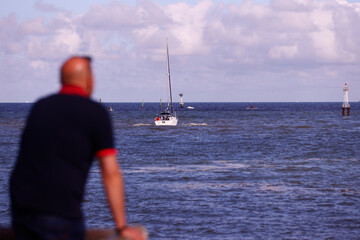 Naklejka premium Back view of a man watching boats on the sea. Trouville. France.