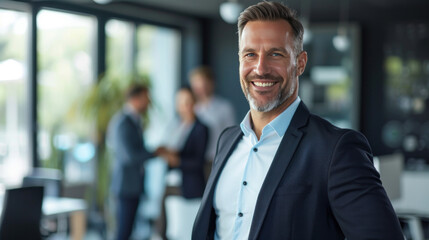 Portrait of a handsome smiling businessman boss standing in his modern business company office.