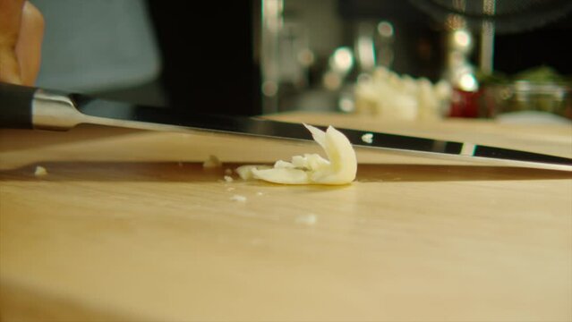 4k Slow Motion close up knife crush and smash garlic on cutting board