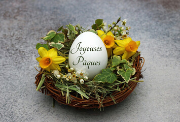 Panier de Pâques décoratif avec des jonquilles, du lierre et un œuf de Pâques étiqueté avec...