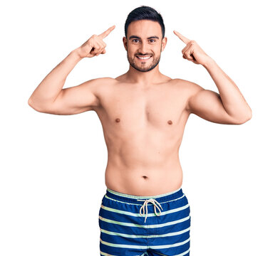 Young handsome man wearing swimwear smiling pointing to head with both hands finger, great idea or thought, good memory