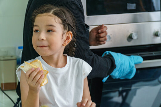 Little girl eating homemade bread Happily in the kitchen