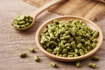 close up green pellet hops in wood spoon and bowl on wooden table food background