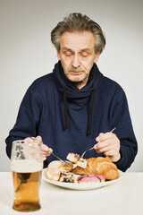 Older man eating sweet pastry and cakes as a meal in studio