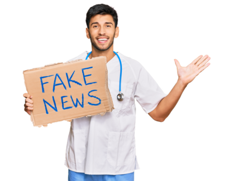 Young handsome man wearing doctor uniform holding fake news banner celebrating victory with happy smile and winner expression with raised hands