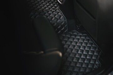 A sophisticated and luxurious leather floor mat in the second row of a modern car. The interior is...
