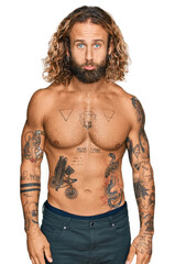 Fototapeta premium Handsome man with beard and long hair standing shirtless showing tattoos depressed and worry for distress, crying angry and afraid. sad expression.