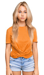 Fototapeta premium Young blonde girl wearing casual clothes with serious expression on face. simple and natural looking at the camera.