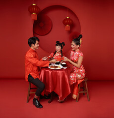 Asian family holding angpao gift in the meal on celebration chinese new year 2024 isolated on red backdrop. Chinese text means Have a wish Blessing 5, good luck and much happiness, rich