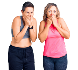 Couple of women wearing sportswear laughing and embarrassed giggle covering mouth with hands, gossip and scandal concept