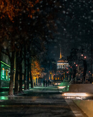 Fototapeta premium Winter night landscape. Blur the background. City evening snow. Cold weather. People walk around the city. Picturesque view. Ukrainian city during the war.