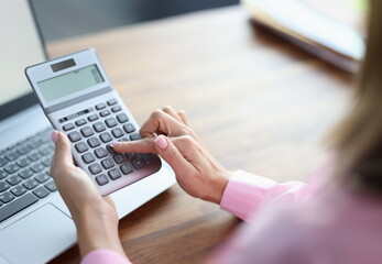 Woman's finger presses button on calculator. Accounting services concept